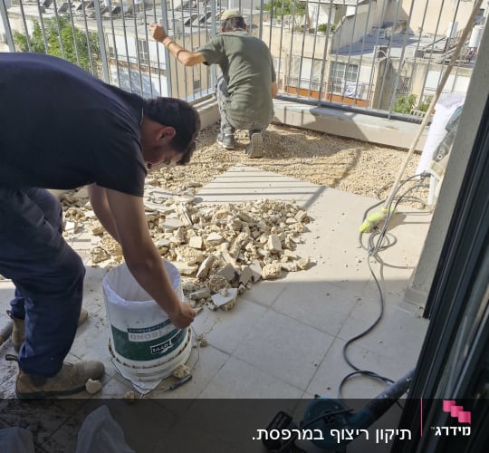 שני פועלים משפצים מרפסת עם כלי עבודה וחצץ